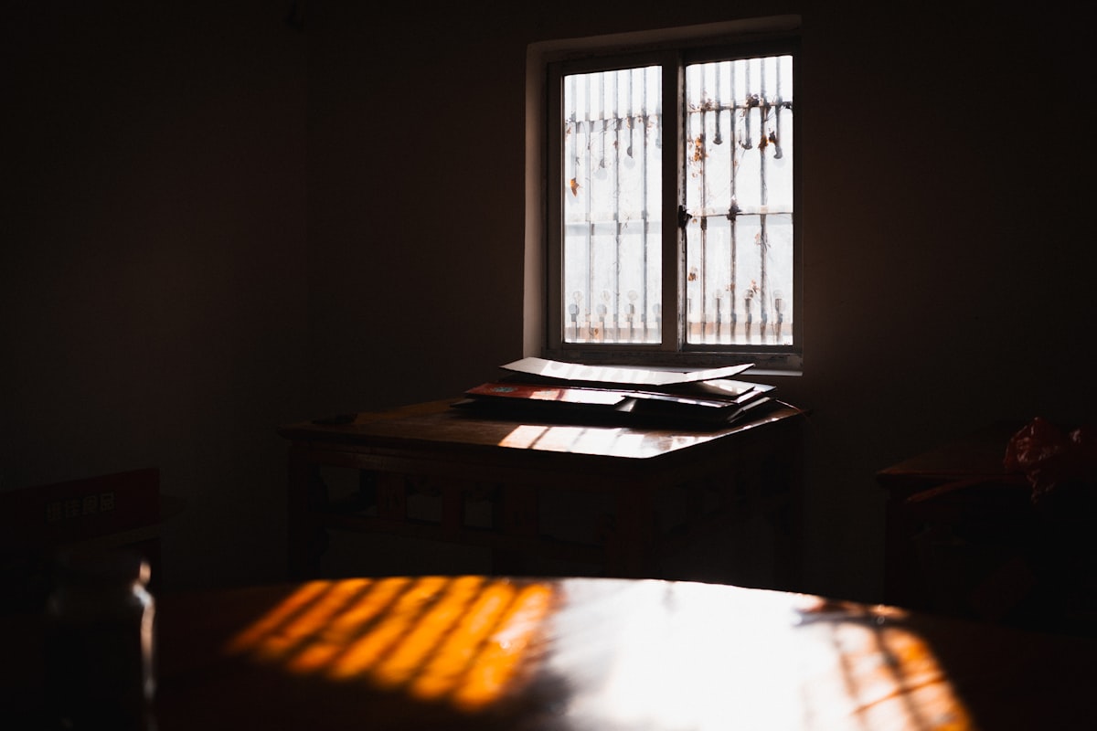 An open notebook and pen on a calm table beside a window with soft daylight falling across the blank page