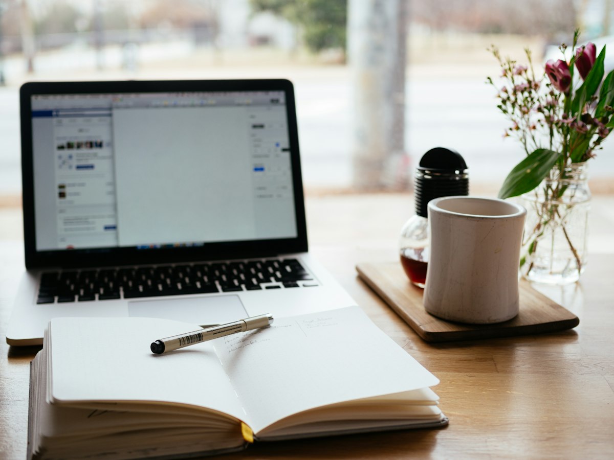 An open notebook beside a laptop on a desk, set up for a quiet moment of reflection on work