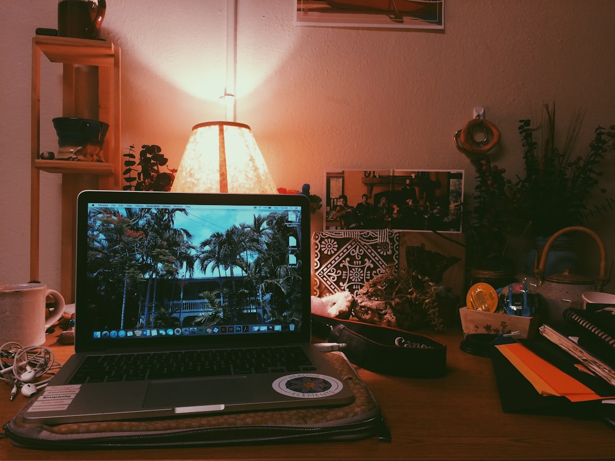 A laptop and notebook on a table in warm light