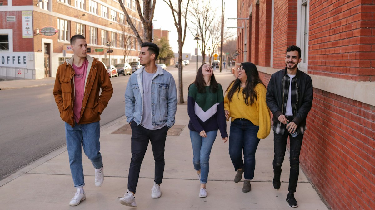 A group of friends laughing as they walk side by side outdoors