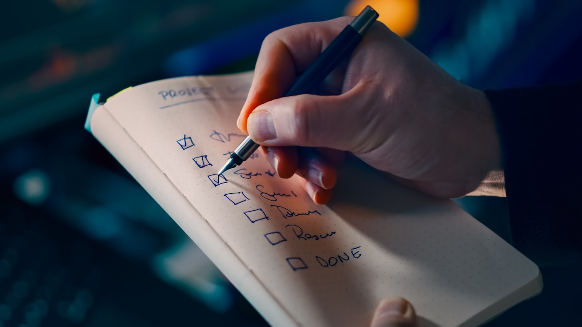 A hand checking off items on a to-do list in a notebook