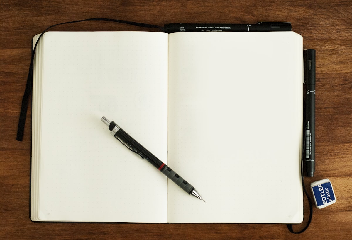 A black and silver pen resting on the blank page of an open notebook
