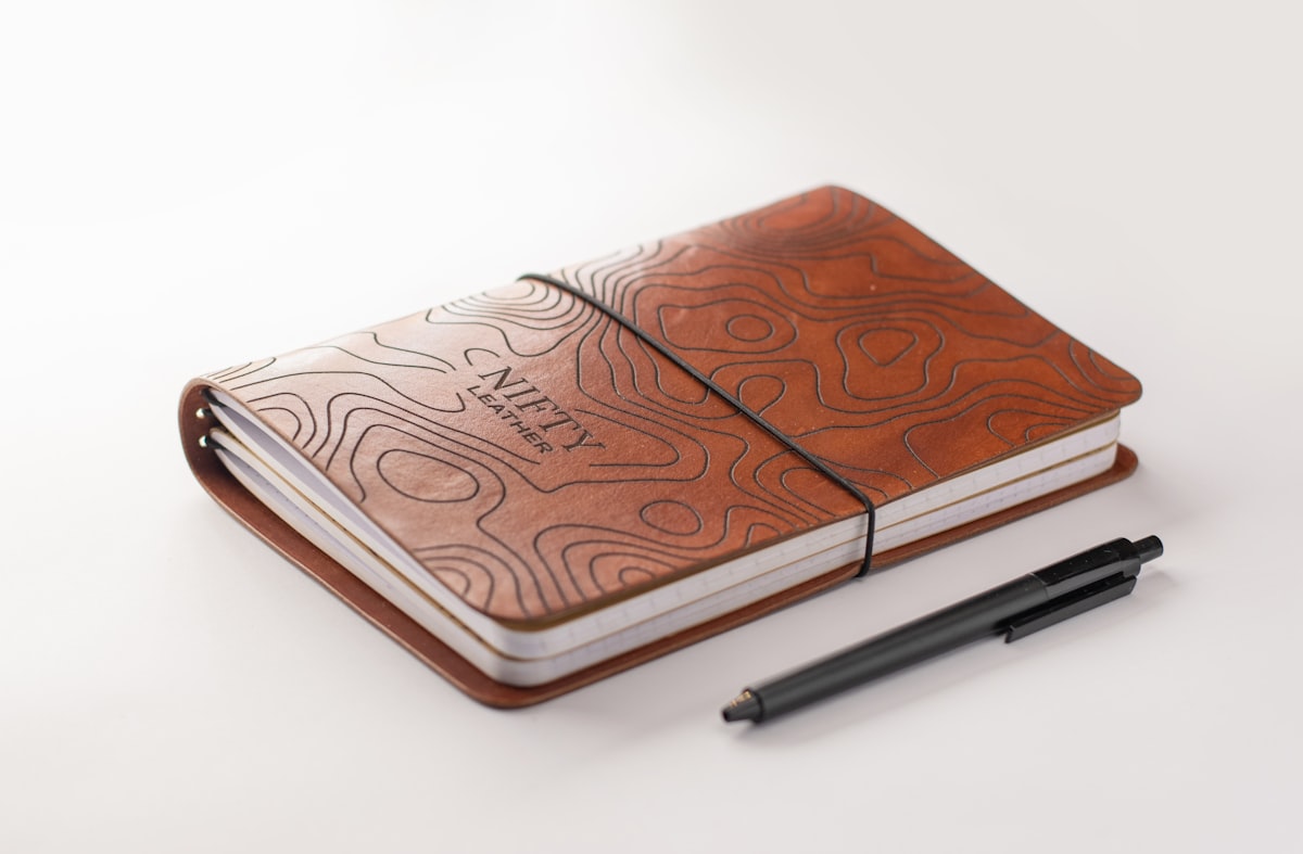 A closed notebook with a pen resting on top, suggesting a private personal journal