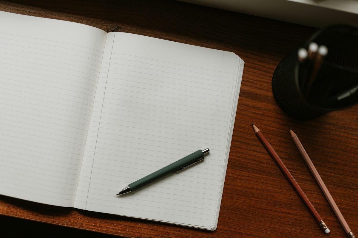 Open notebook with pen and pencils on a desk