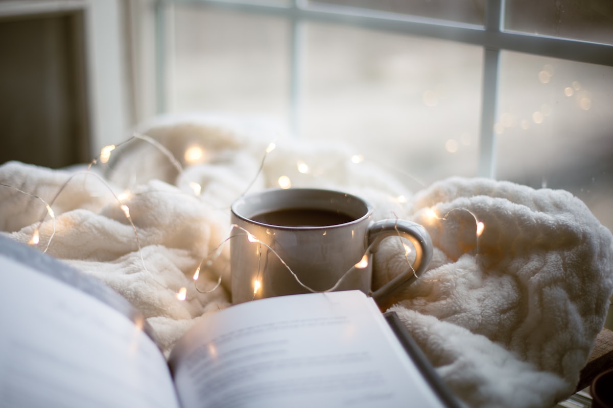 An open notebook resting on a blanket beside a warm cup, suggesting rest and slow recovery