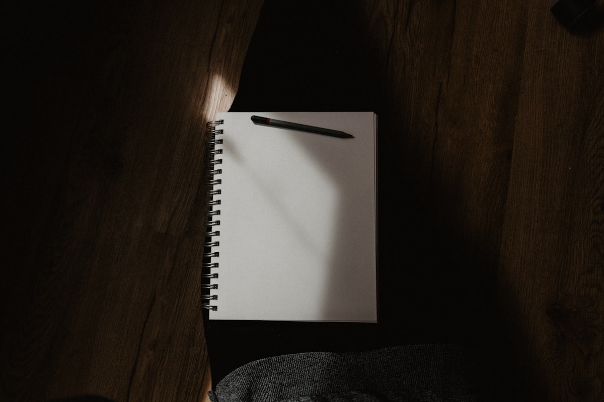 A white spiral notebook open on a dark surface, ready for writing