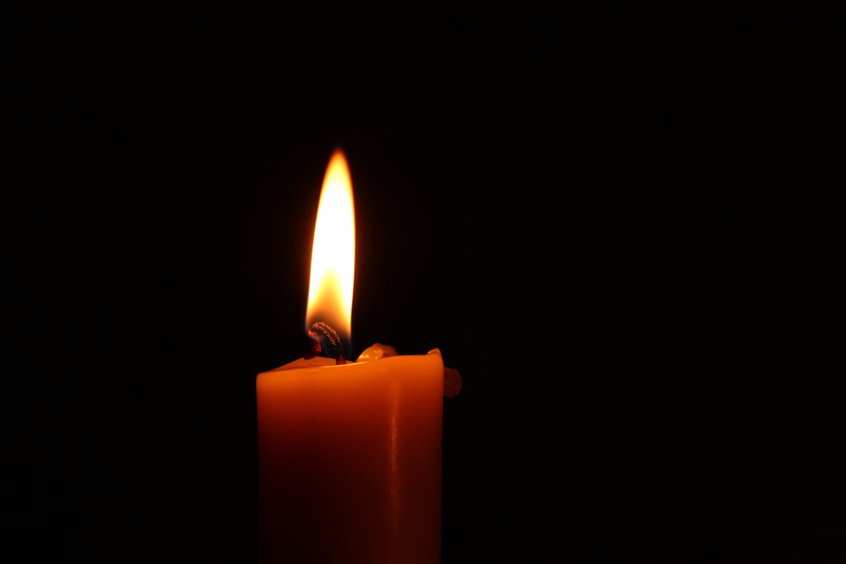 A single lit candle against a dark background, a quiet image of remembrance