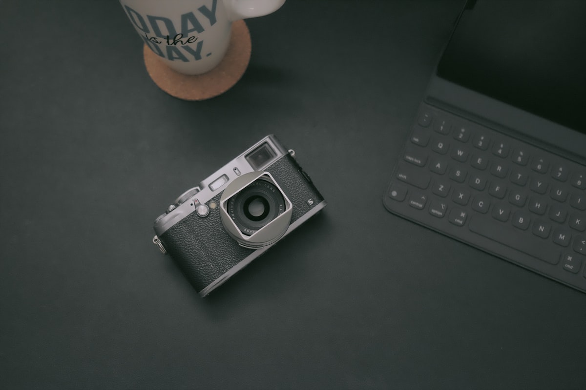A camera resting on a table beside a keyboard, suggesting a photographer's working setup
