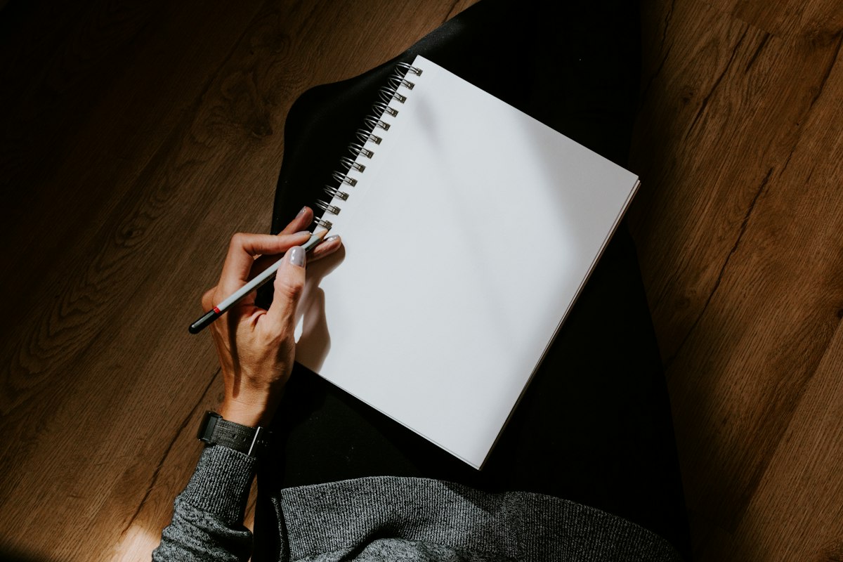 A person writing by hand on a sheet of white paper, starting a journal in later life