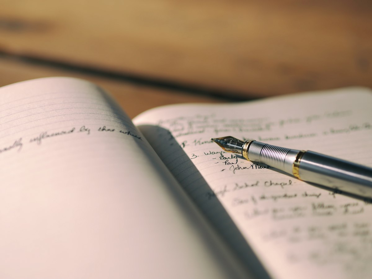 A pen resting on white lined paper with handwritten lines