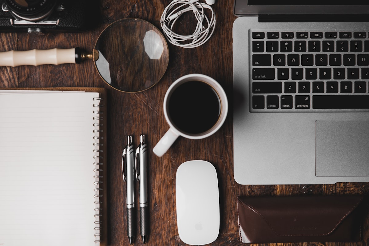 A cup of coffee on a desk beside a laptop