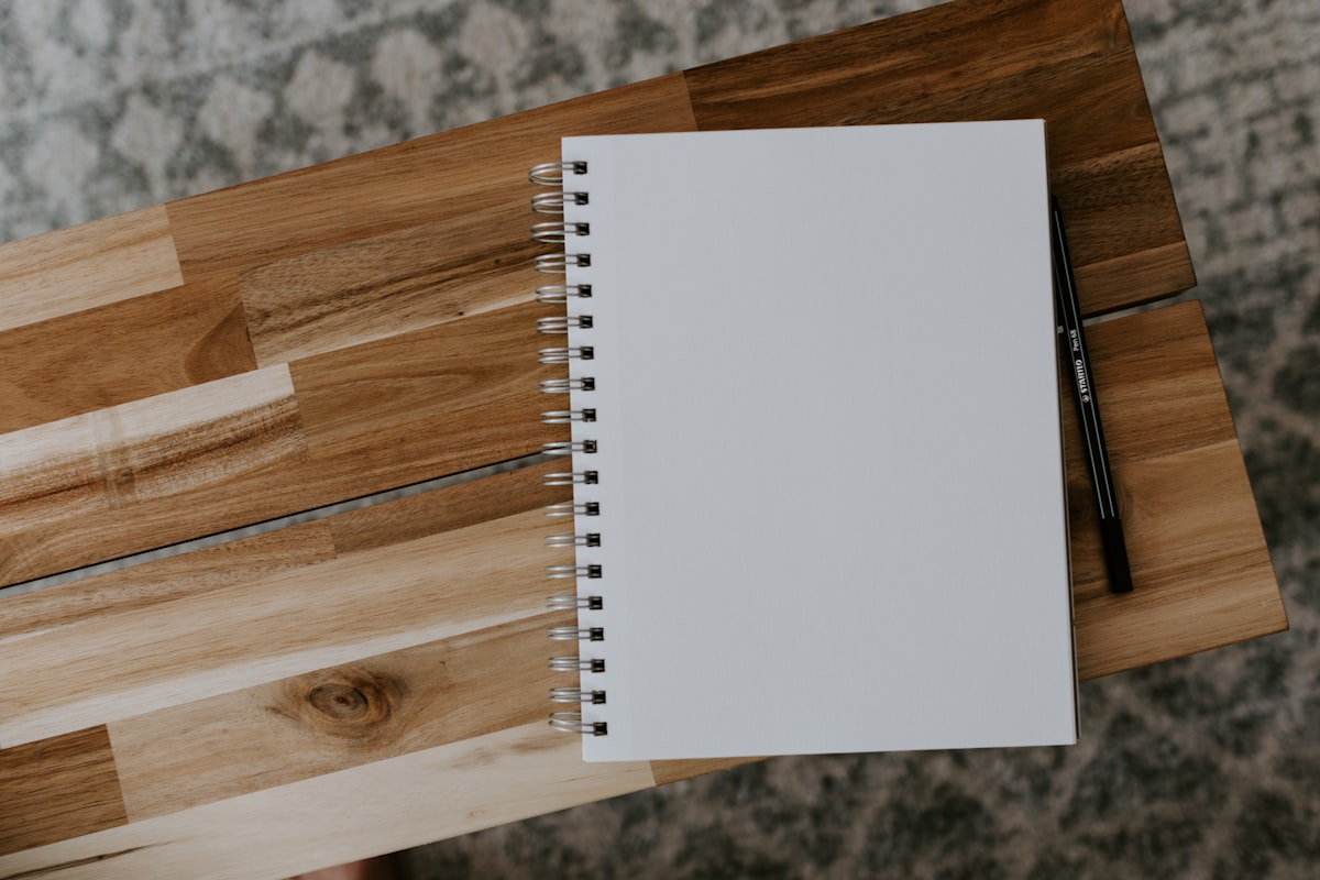 A white spiral notebook on a brown wooden table