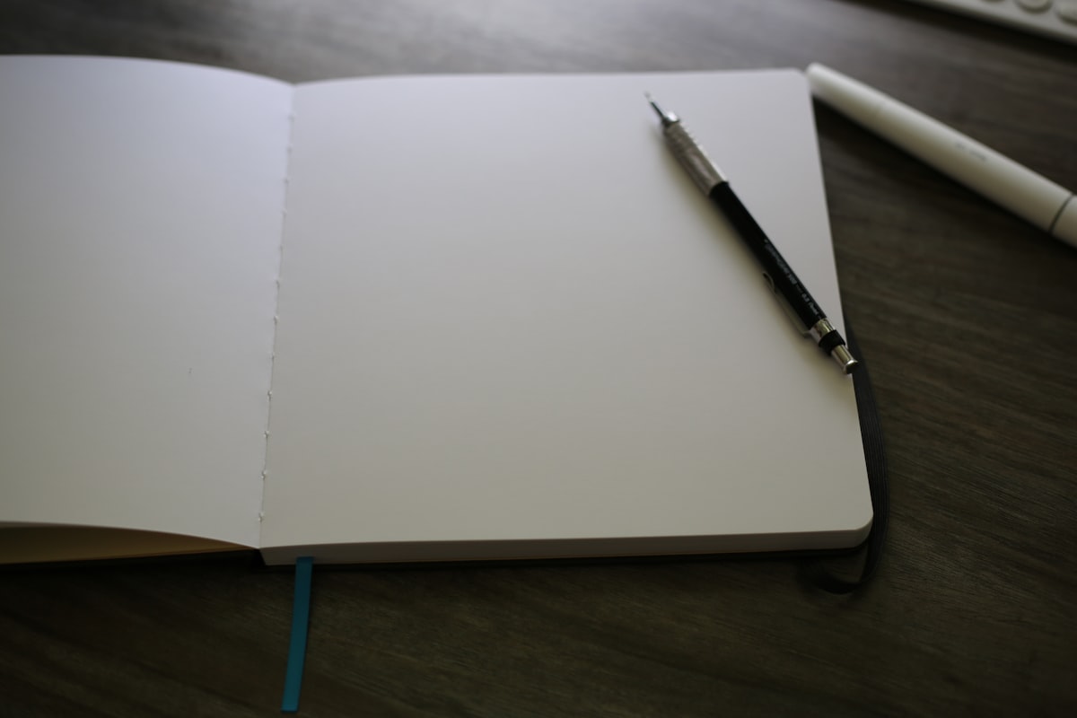 An open notebook with a pen resting on top, evoking a pause before writing