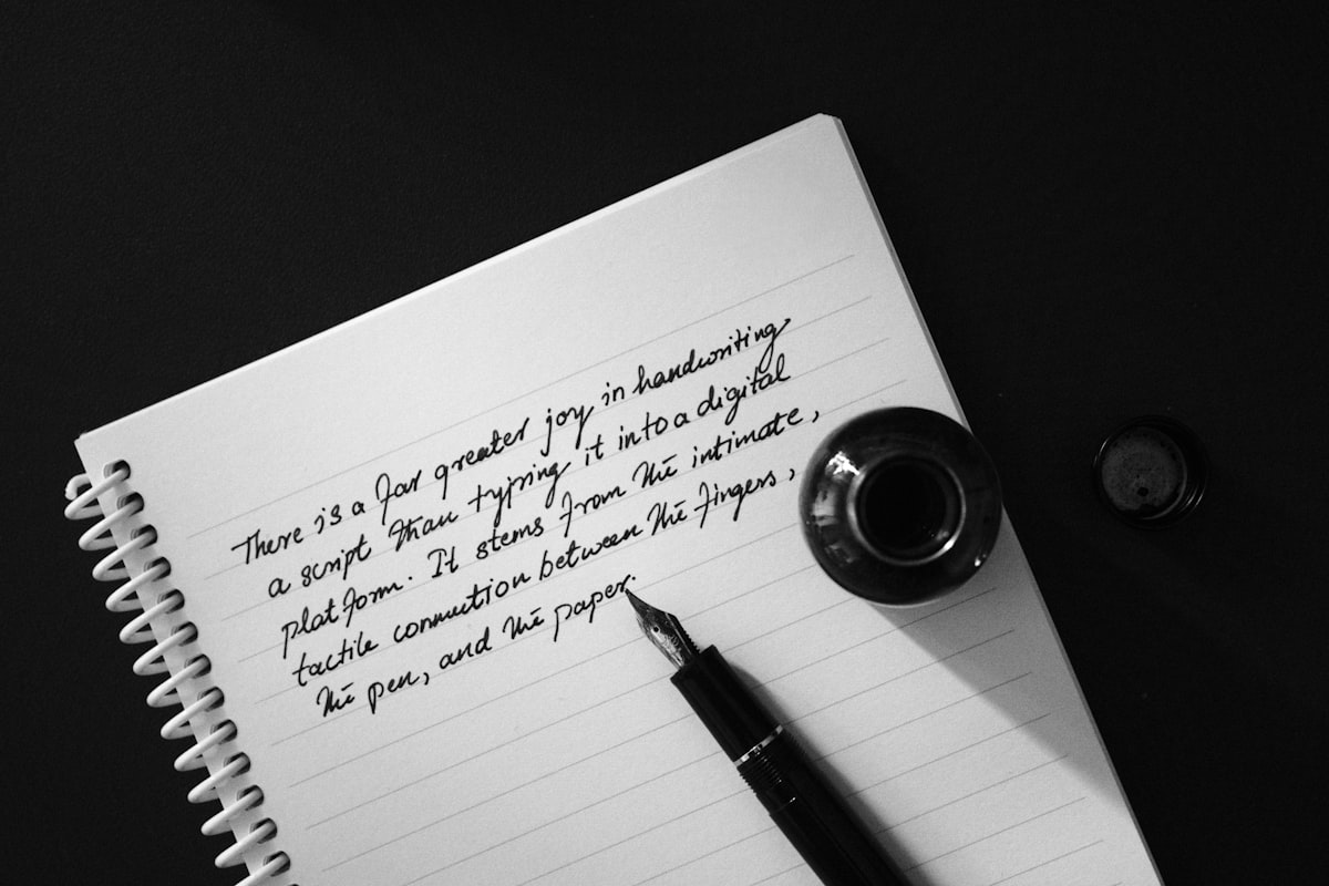 A fountain pen and inkwell resting on an open notebook
