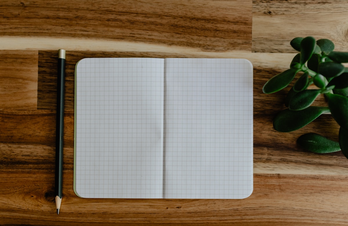 An open notebook, a pen, and a few small keepsakes arranged on a wooden table