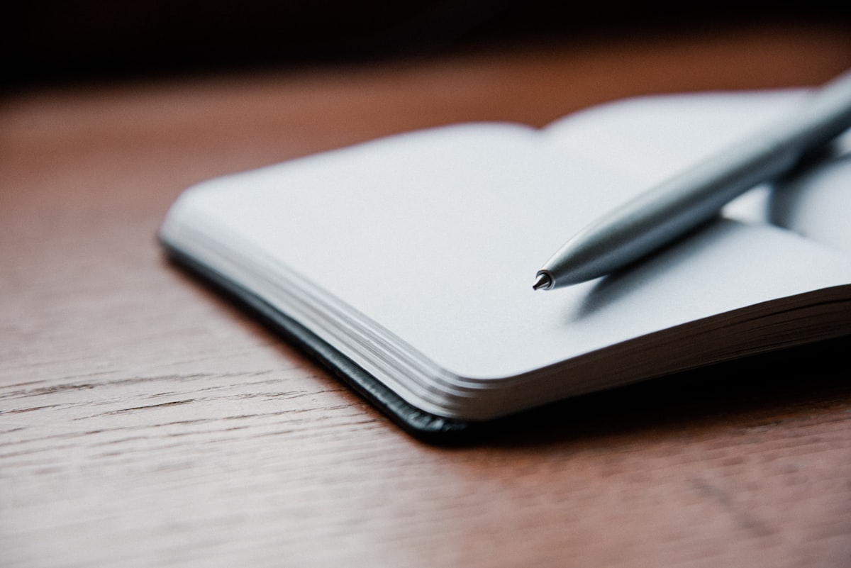 A gray ballpoint pen resting on top of an open white notebook