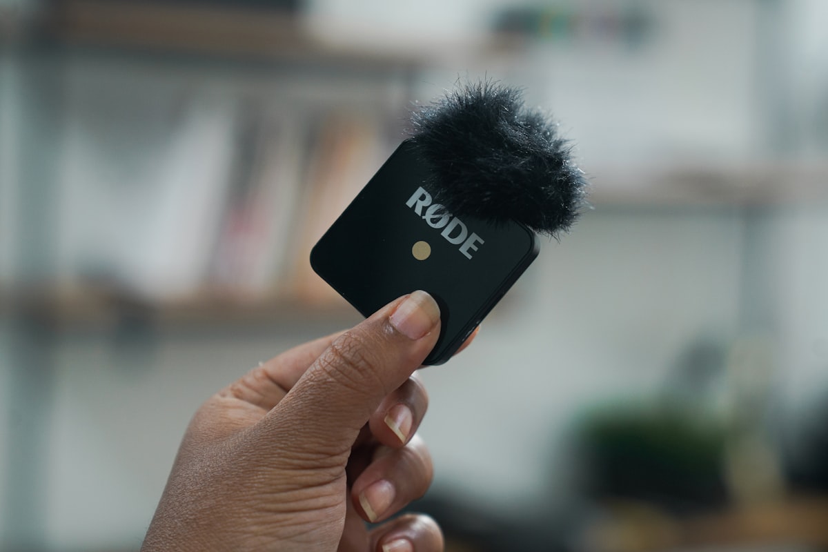 A person holding a small audio recording device in their hand