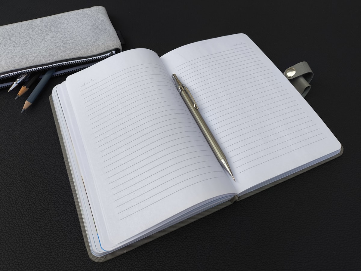 A notebook with a pen and pencils on a minimal desk